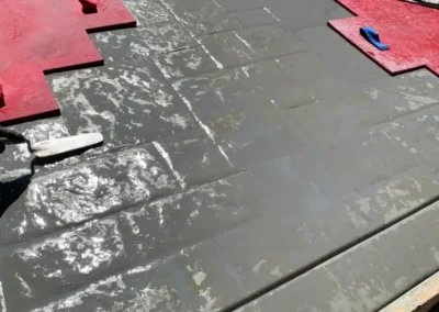 Wet concrete being stamped with brick paver pattern